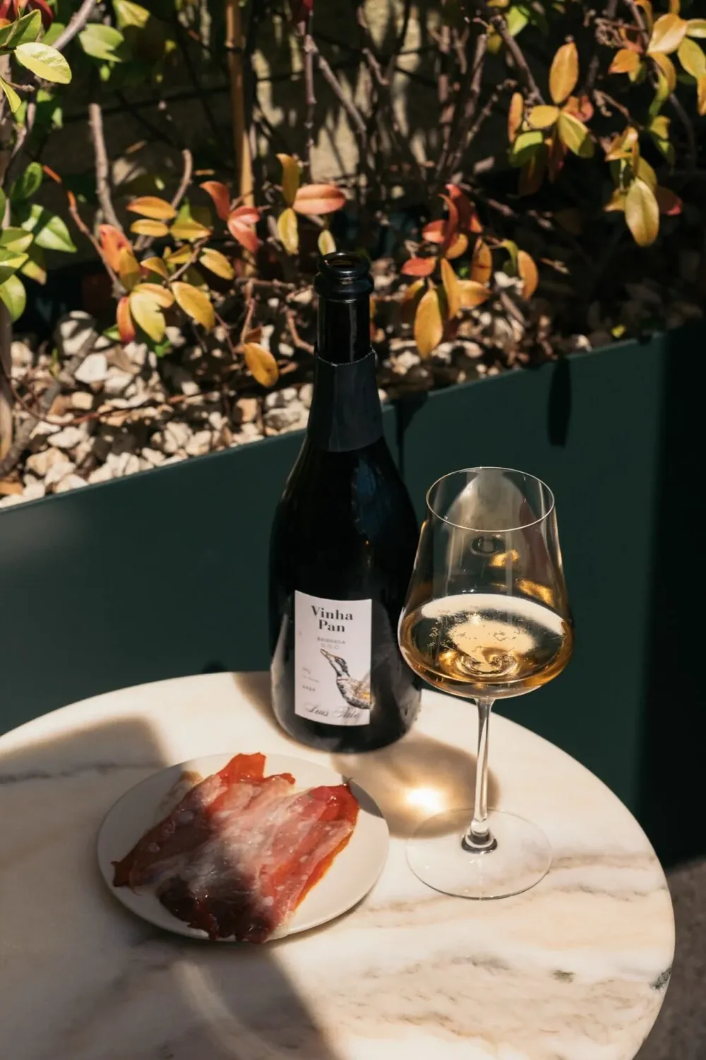 Garrafa e copo de vinho branco numa mesa de mármore